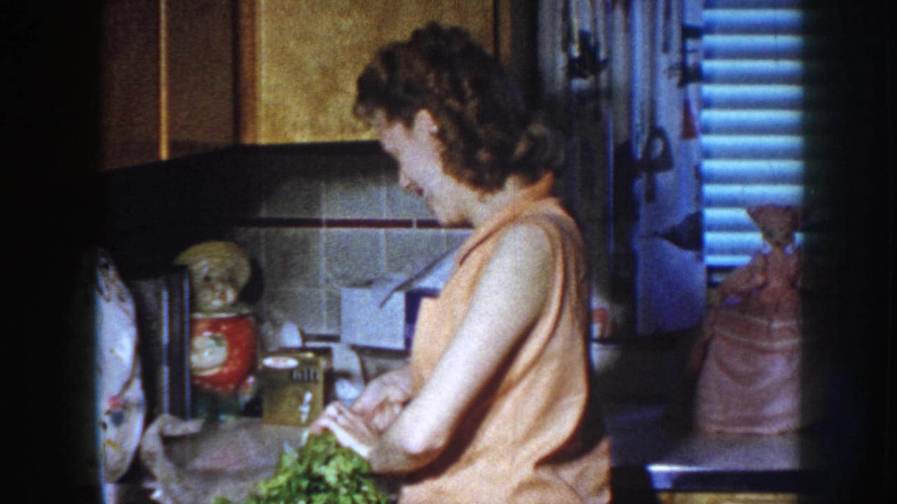 Woman in a kitchen cutting greens at a counter.