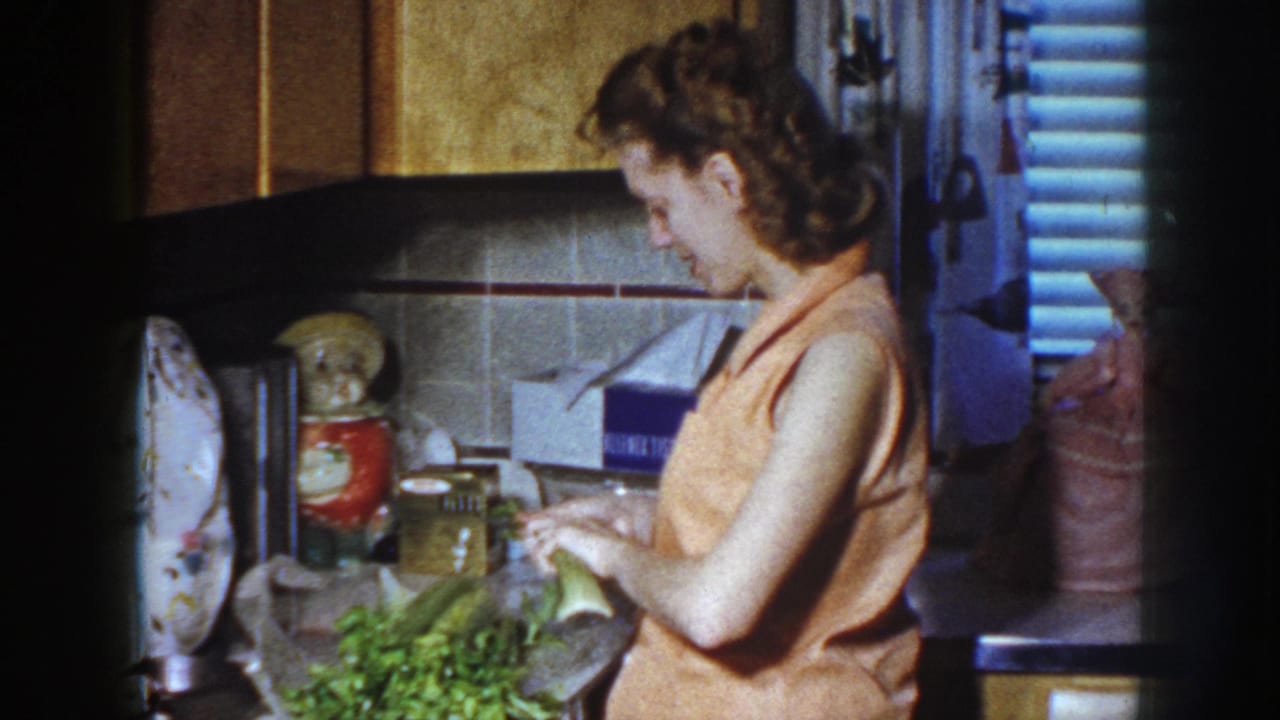 Woman looking down while preparing vegetables on a kitchen counter.
