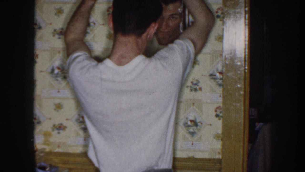 Man seen from behind raising both arms while looking into a wall mirror.