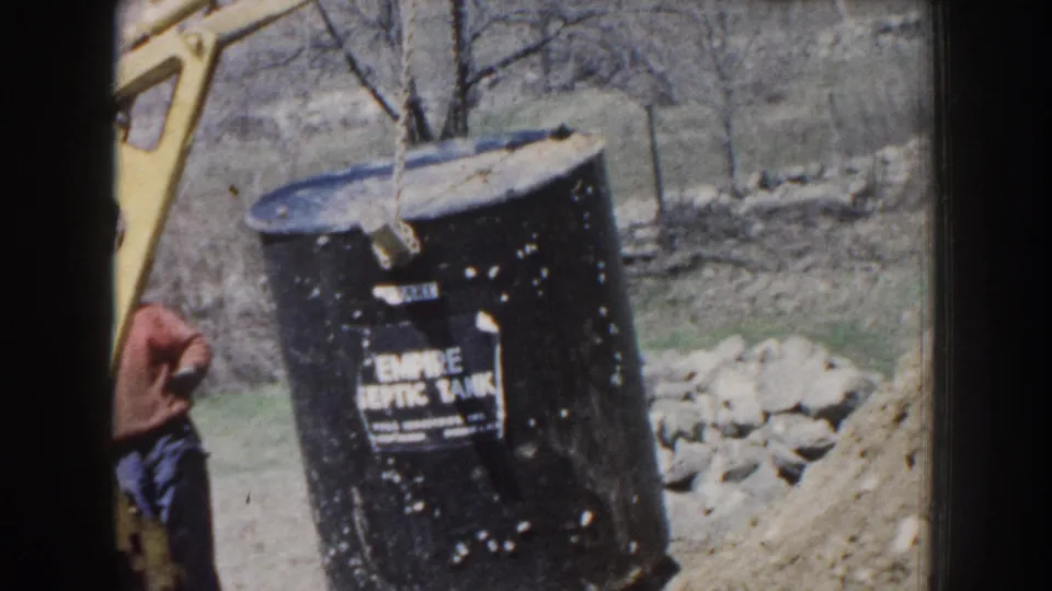 Black Empire Septic Tank label is visible as the tank hangs from a chain at a rural Nebraska worksite in 1959 footage.
