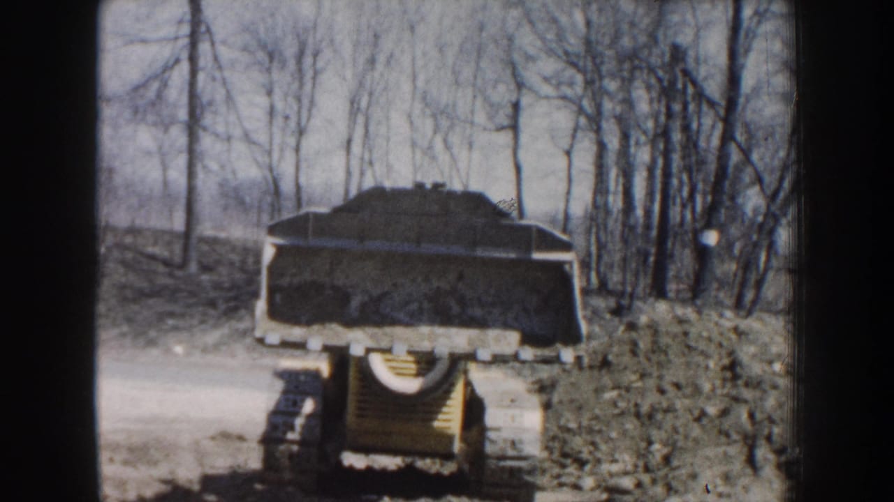 Rear view of the loader with its bucket raised on a dirt path.