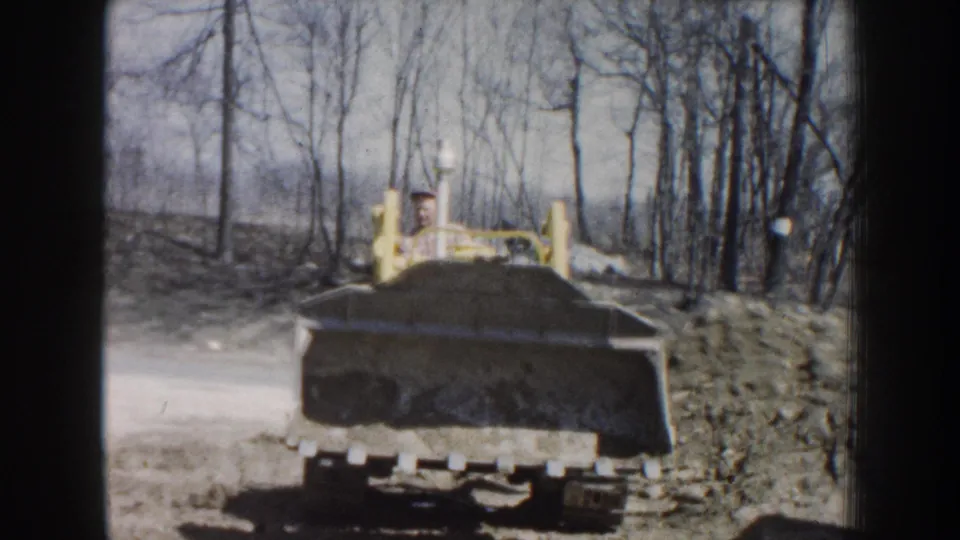 1959 Nebraska frame showing the loader from behind, with the operator visible above the raised equipment arms.