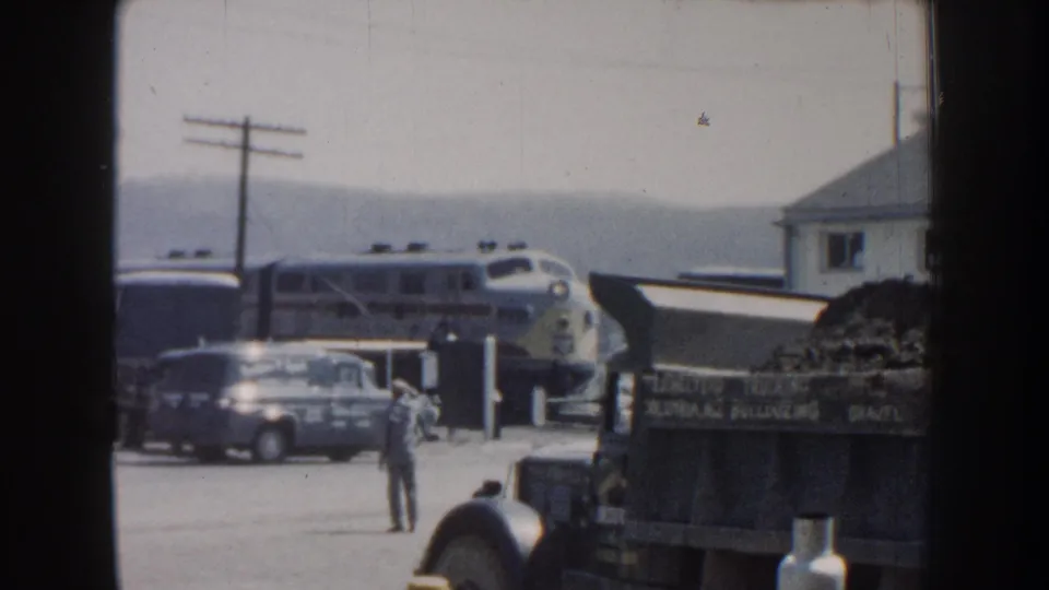 Later station view of the passenger train, van, small building, and standing man in the 1959 Nebraska footage.