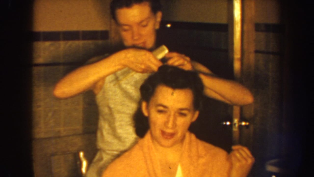 Woman using a comb on another woman’s hair in a bathroom.