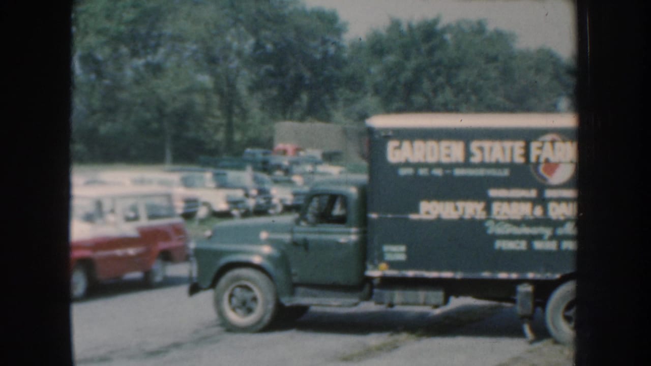 Green Garden State Farm Supply truck parked near period cars in a lot.