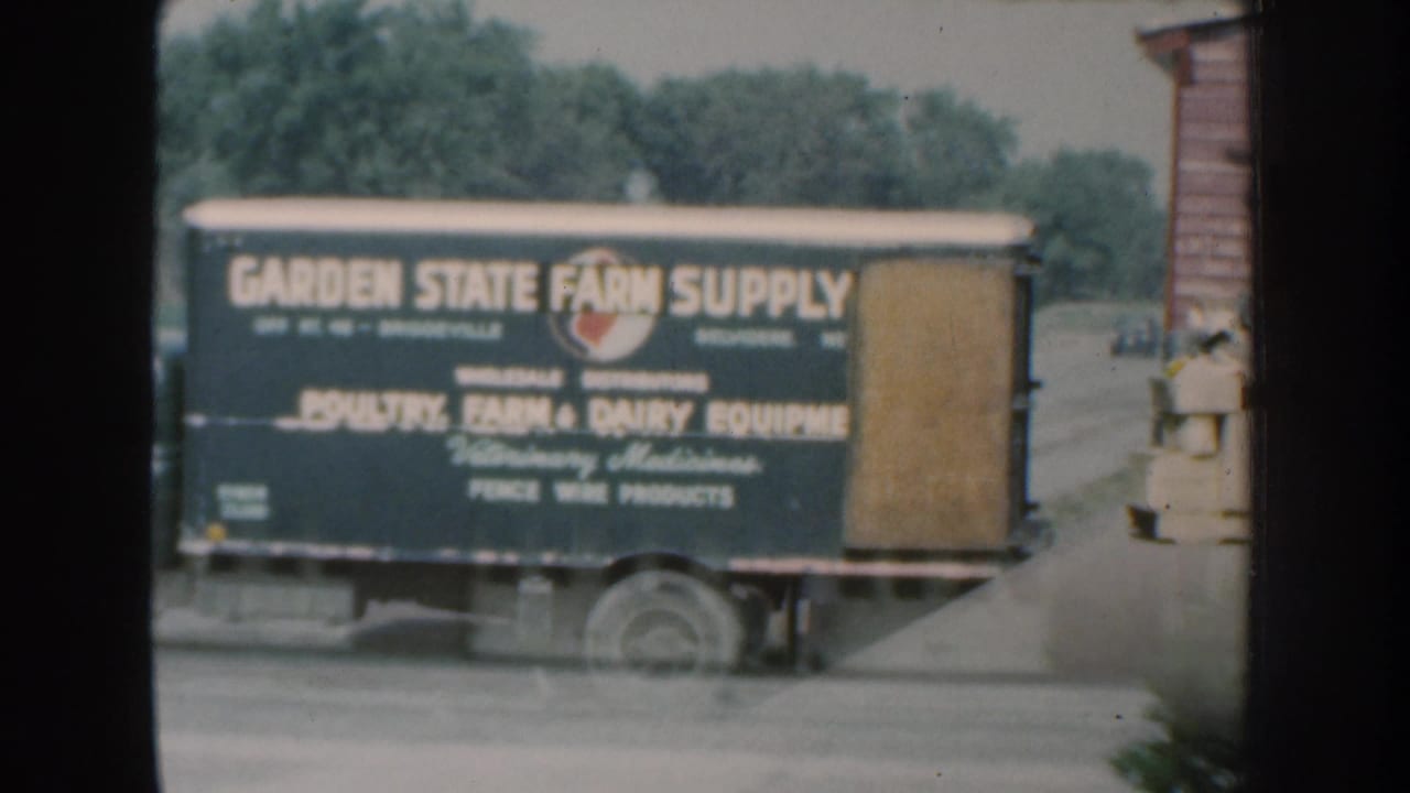 1959 Nebraska home-movie frame with the rear side of the Garden State Farm Supply truck and its painted equipment advertising.
