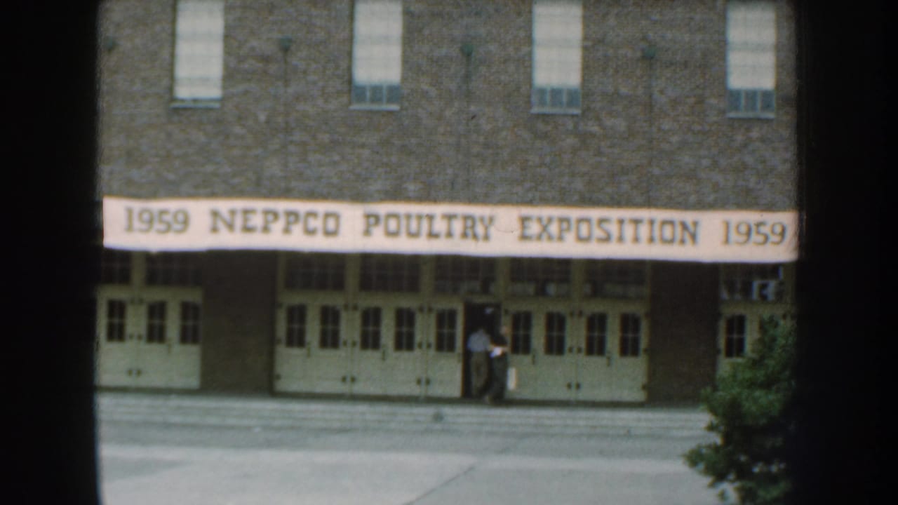 Brick exposition building in Nebraska with a banner reading 1959 NEPPCO Poultry Exposition and a person near the entrance.