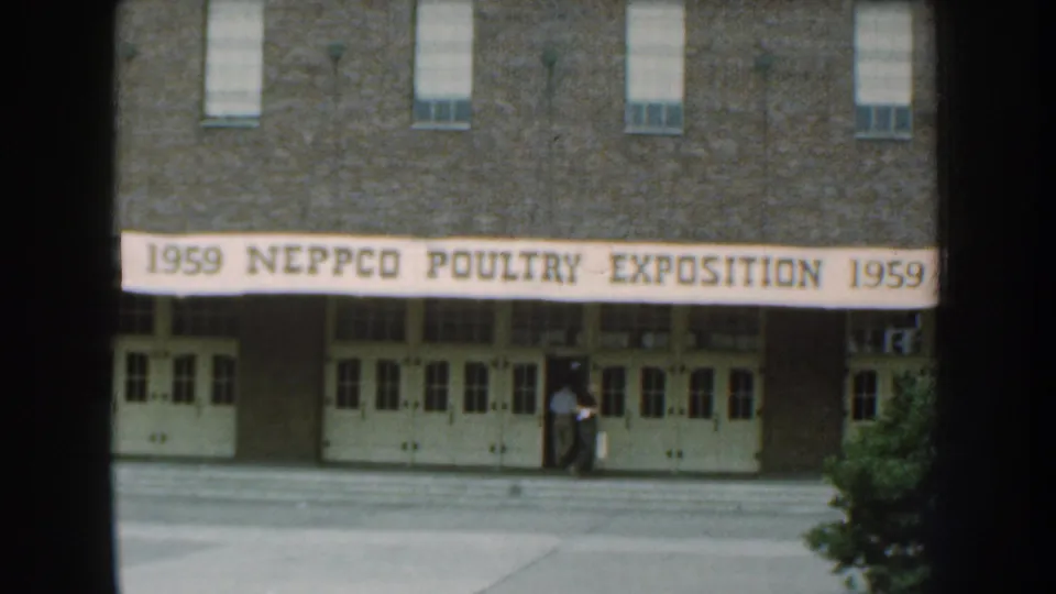 Brick exposition building in Nebraska with a banner reading 1959 NEPPCO Poultry Exposition and a person near the entrance.