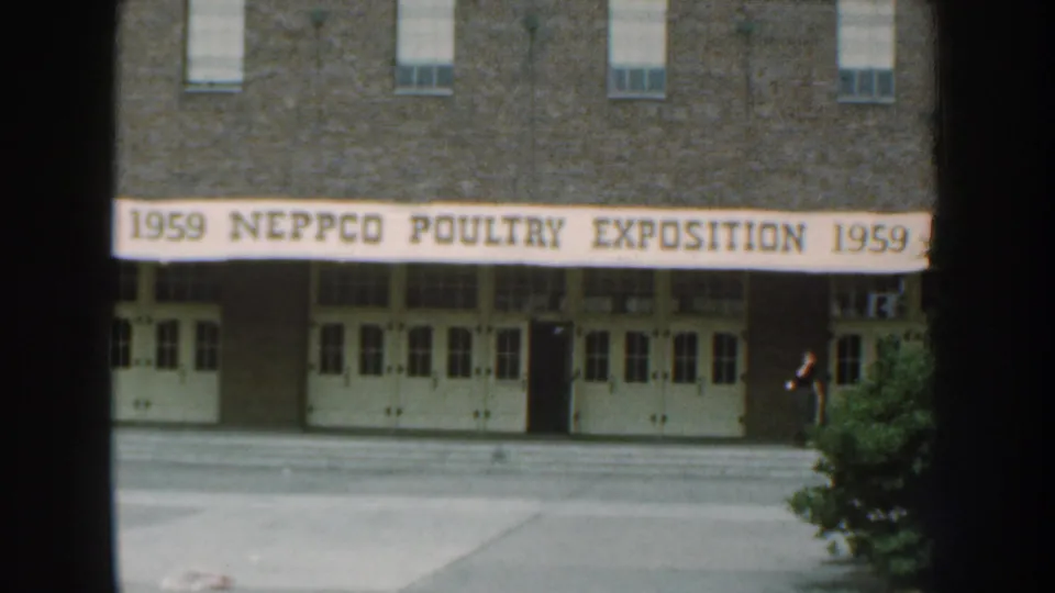 1959 Nebraska exterior view of a brick building with a NEPPCO Poultry Exposition banner over white doors.
