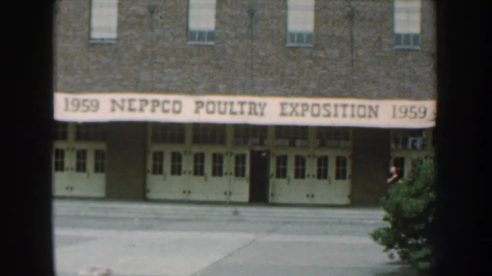 1959 Nebraska exposition exterior with a lone adult man standing near the right side of the entrance area.