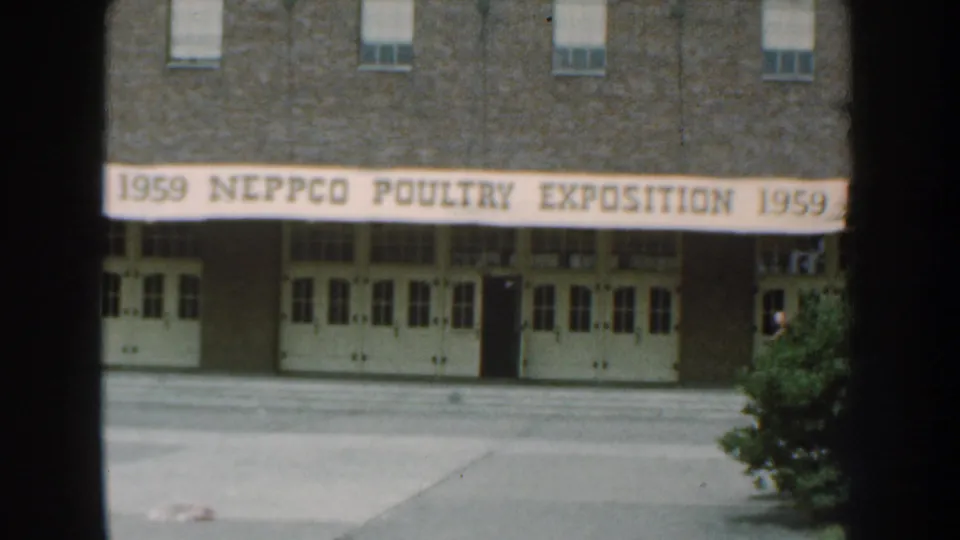 Home-movie view of the NEPPCO Poultry Exposition banner across a brick building in Nebraska, 1959.