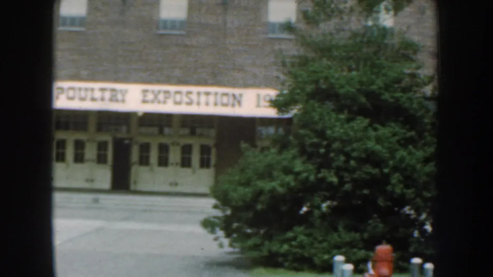 1959 Nebraska exterior view of the NEPPCO Poultry Exposition building, with the banner crossing the facade and trees at right.