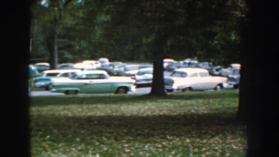 The final 1959 Nebraska frame shows parked mid-century automobiles partly obscured by trees and shade.