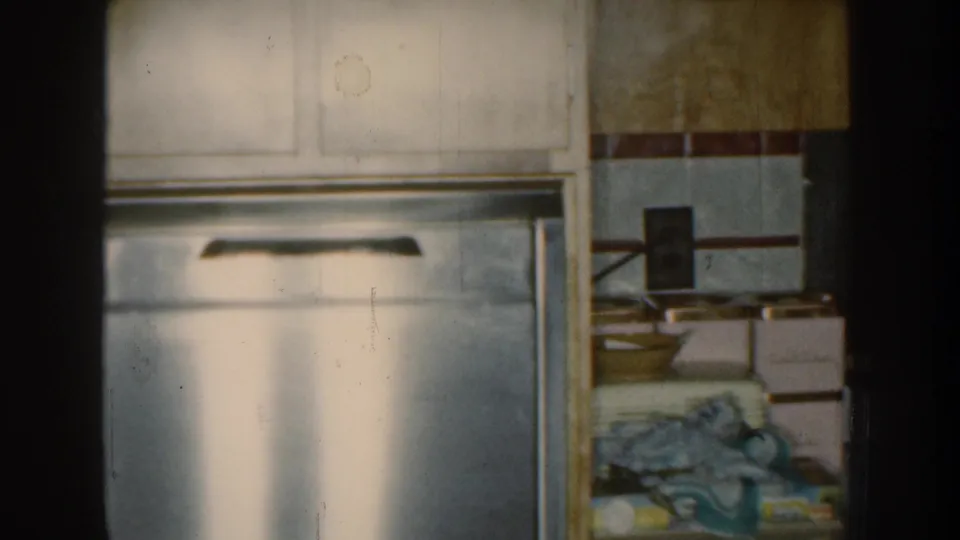 The final frame shows a metal refrigerator, tiled wall and stacked household items in the same private Nebraska kitchen interior.