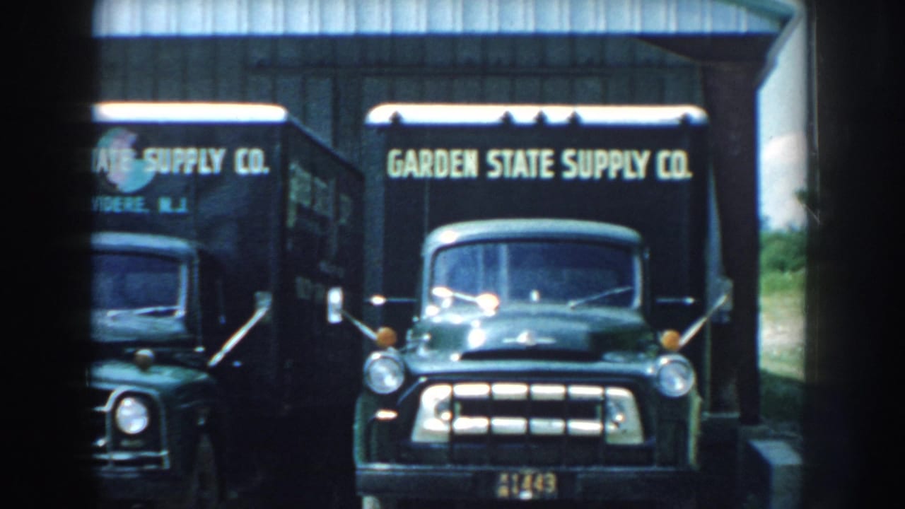 Two Garden State Supply Co trucks appear under a corrugated metal canopy in this 1959 Nebraska home-movie frame.
