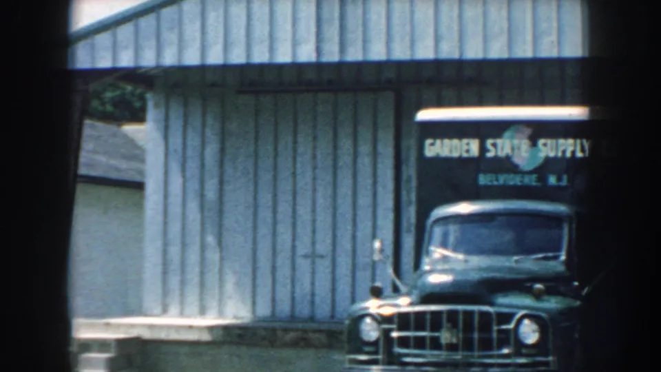 A Garden State Supply Co truck sits near a corrugated metal wall, with 8mm frame edges visible around the 1959 Nebraska scene.