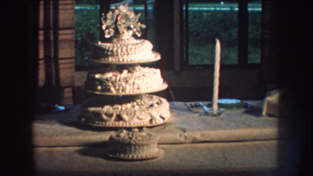 Decorated wedding cake and candle on a table, seen through dark 8mm frame edges.
