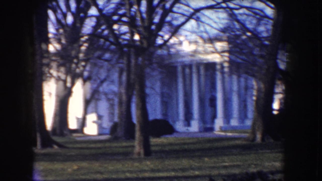 White House exterior in Washington, D.C., framed by bare winter trees in vintage 8mm footage.