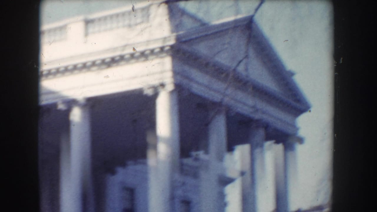 A Washington, DC civic building appears in soft 8mm color, showing columns, entablature, and a triangular pediment.