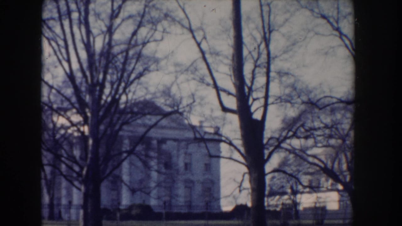 A grand white civic building in Washington, DC appears through winter trees and an iron fence in this 1960 home-movie frame.