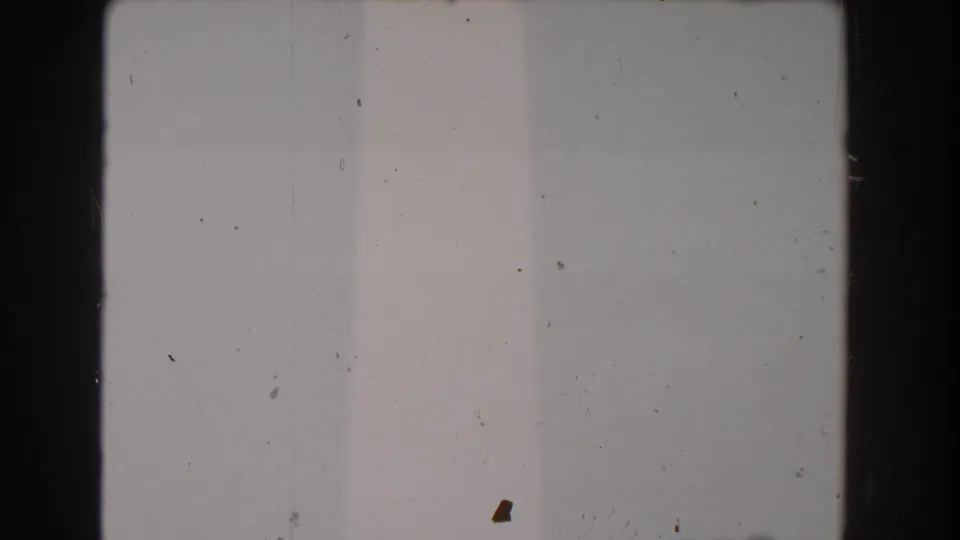 Sparse 8mm frame from Washington, DC showing pale sky, a sliver of the Washington Monument, dust, and rounded film borders.