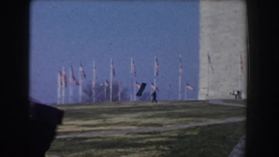 1960 Washington, D.C. home-movie view of the Washington Monument, flags, open lawn, and a distant pedestrian.