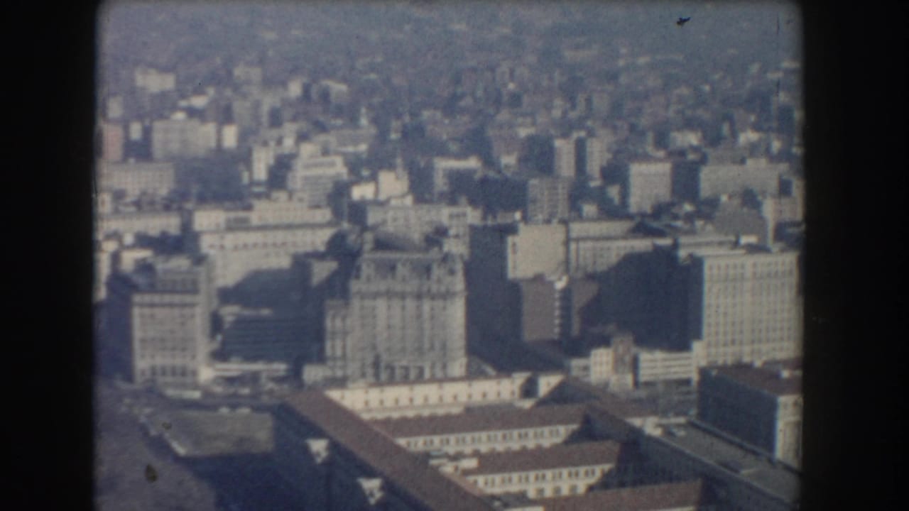 Hazy aerial view of dense city blocks and large civic buildings.