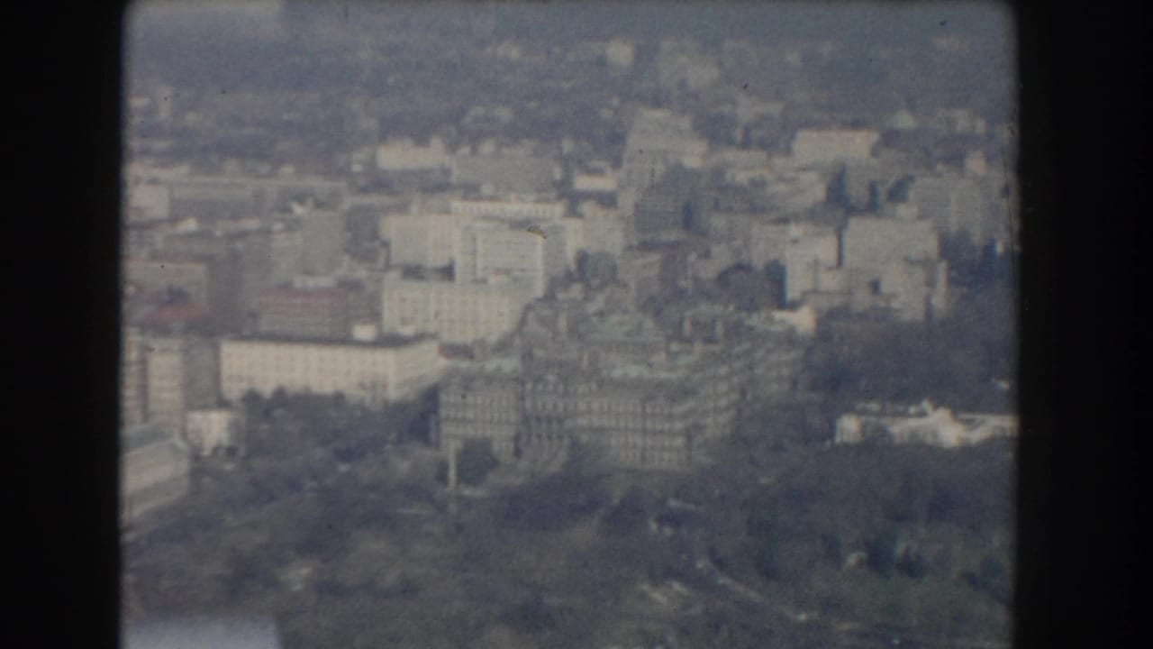 Soft aerial view of Washington, DC buildings, trees, and formal grounds.