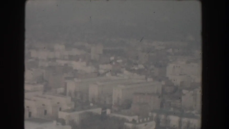 1960 Washington, DC aerial frame showing low-rise buildings, roads, trees, and soft urban detail in grainy home-movie color.