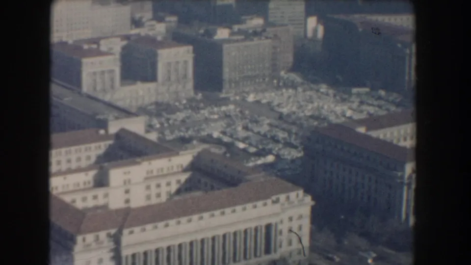 1960 Washington, D.C. aerial frame showing a large classical building, dense parked cars, and surrounding downtown blocks.