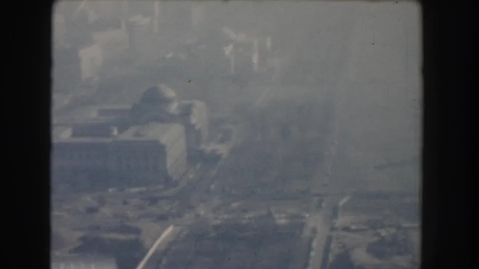 1960 Washington, DC home-movie frame with a hazy aerial view of buildings, roads, and a bridge approach near a river.