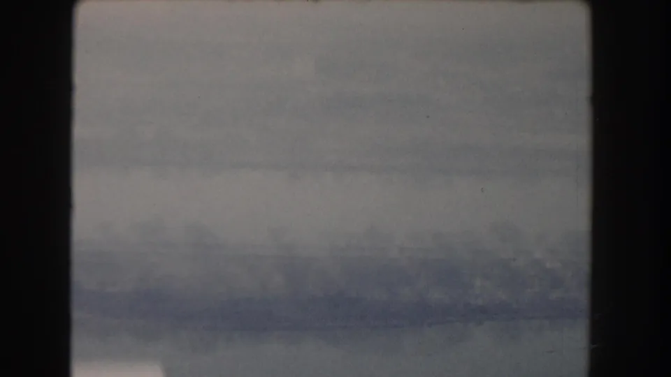 Faded 8mm frame from the 1960 Washington-area clip, showing water, haze, and indistinct shoreline forms in soft focus.