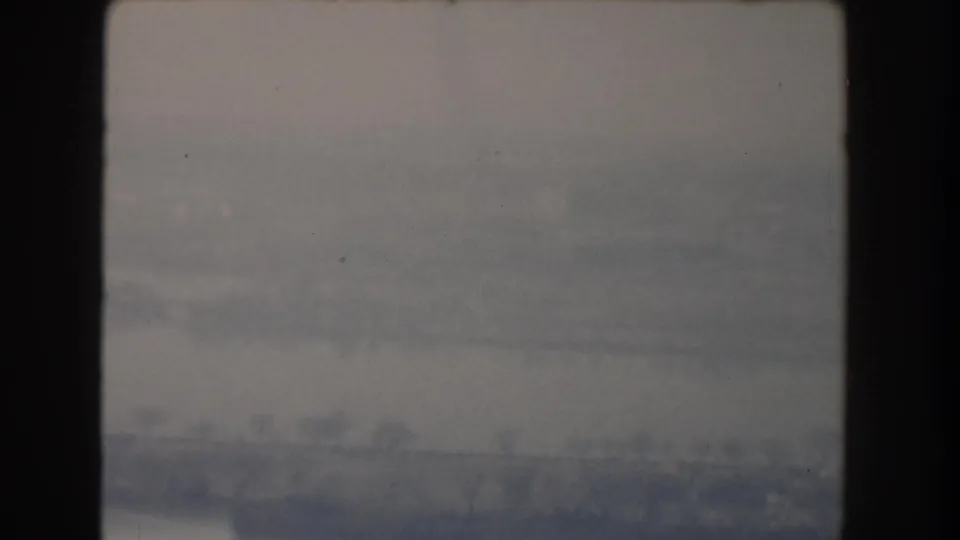 Final 1960 archival frame showing a broad water crossing and indistinct shoreline, with aged 8mm color and soft exposure.