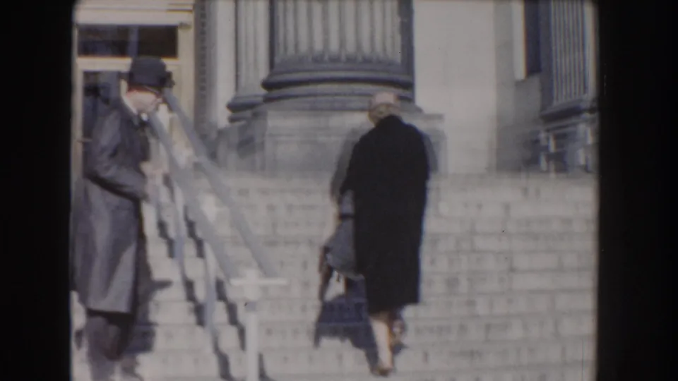 In Washington, DC, 1960, two adults walk up the steps toward the Smithsonian Natural History Building entrance.