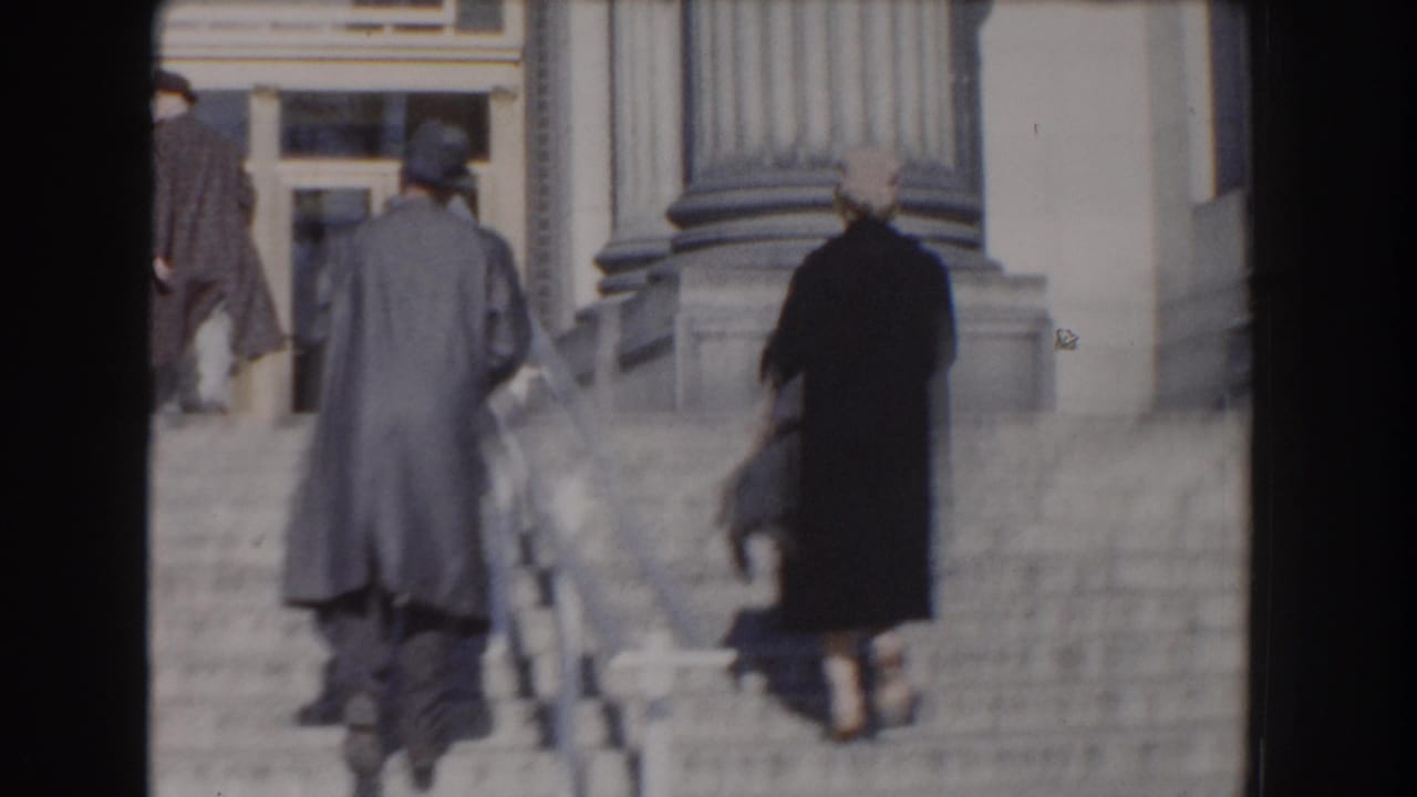 A man and woman continue up the steps toward a columned entrance.
