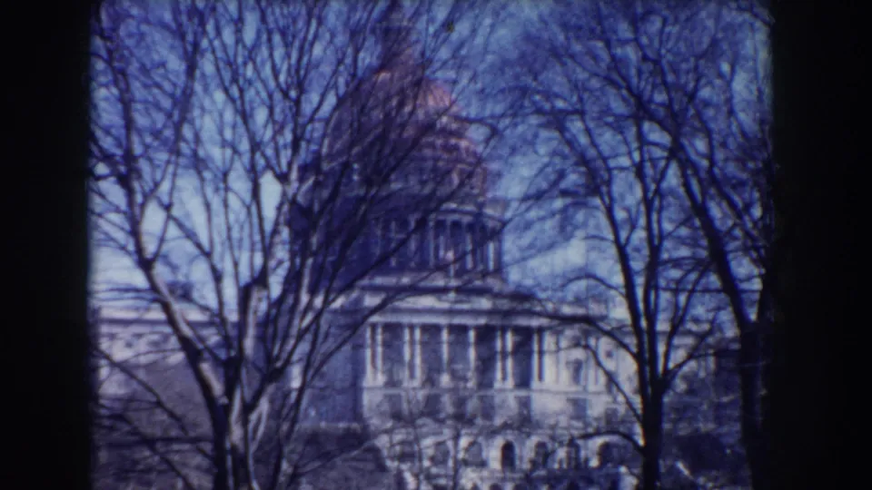 Washington, DC 1960 frame of the U.S. Capitol seen through winter branches, with visible grain and blue color shift.
