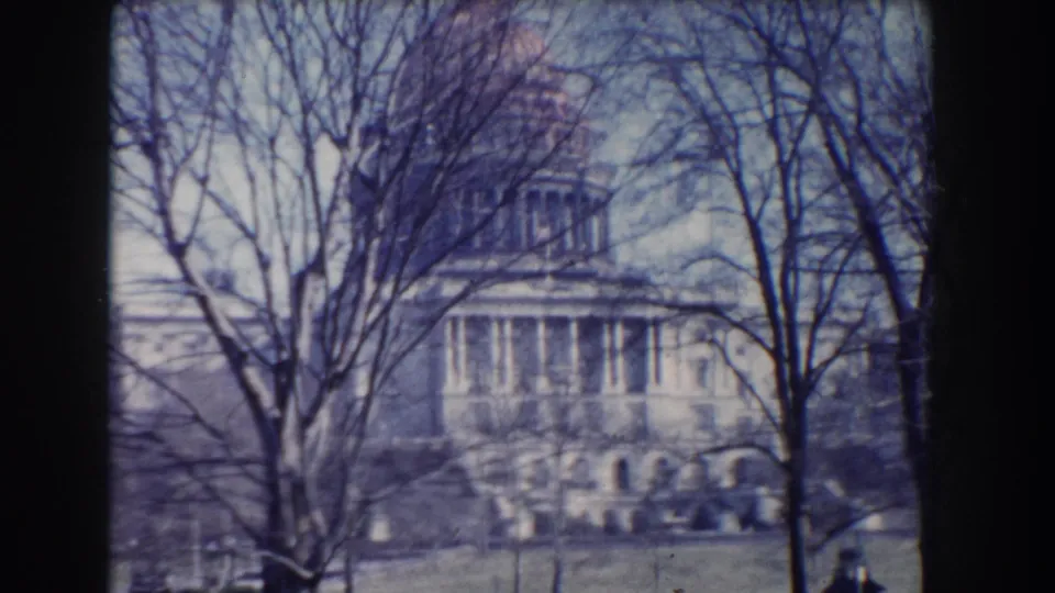 Visitor-shot 1960 view of the U.S. Capitol behind leafless branches and open lawn in Washington, DC.
