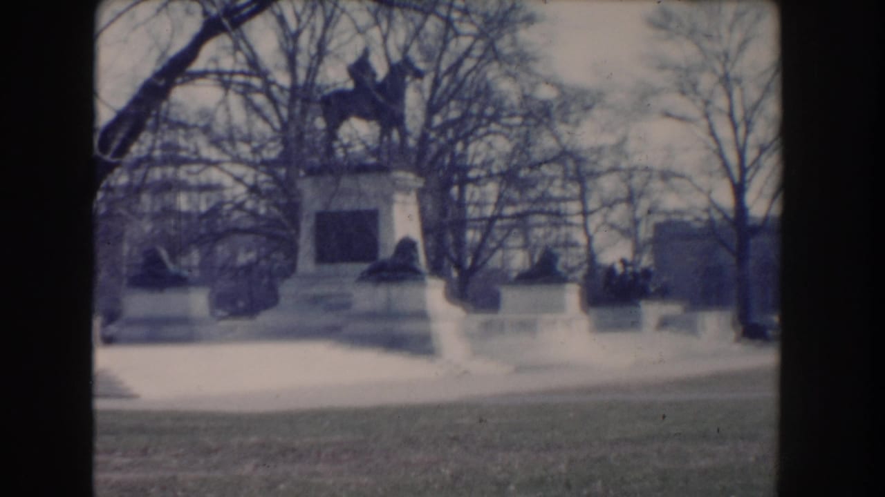 1960 Washington, DC home-movie view of a white park monument framed by bare trees and distant civic buildings.