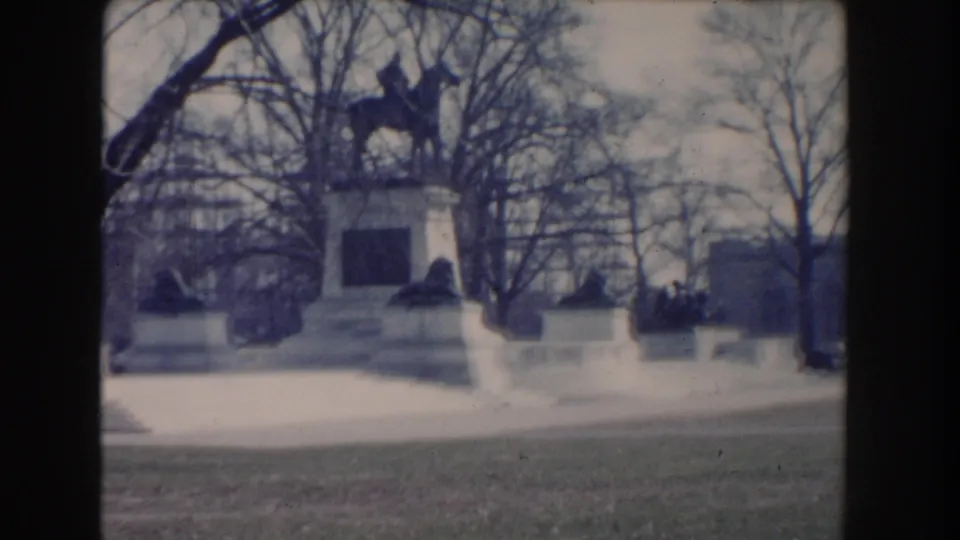 1960 Washington, DC home-movie view of a white park monument framed by bare trees and distant civic buildings.