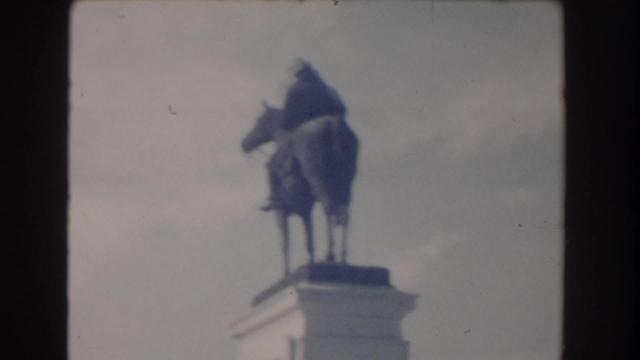 Soft 8mm view of an equestrian statue on a stone pedestal under a pale sky.