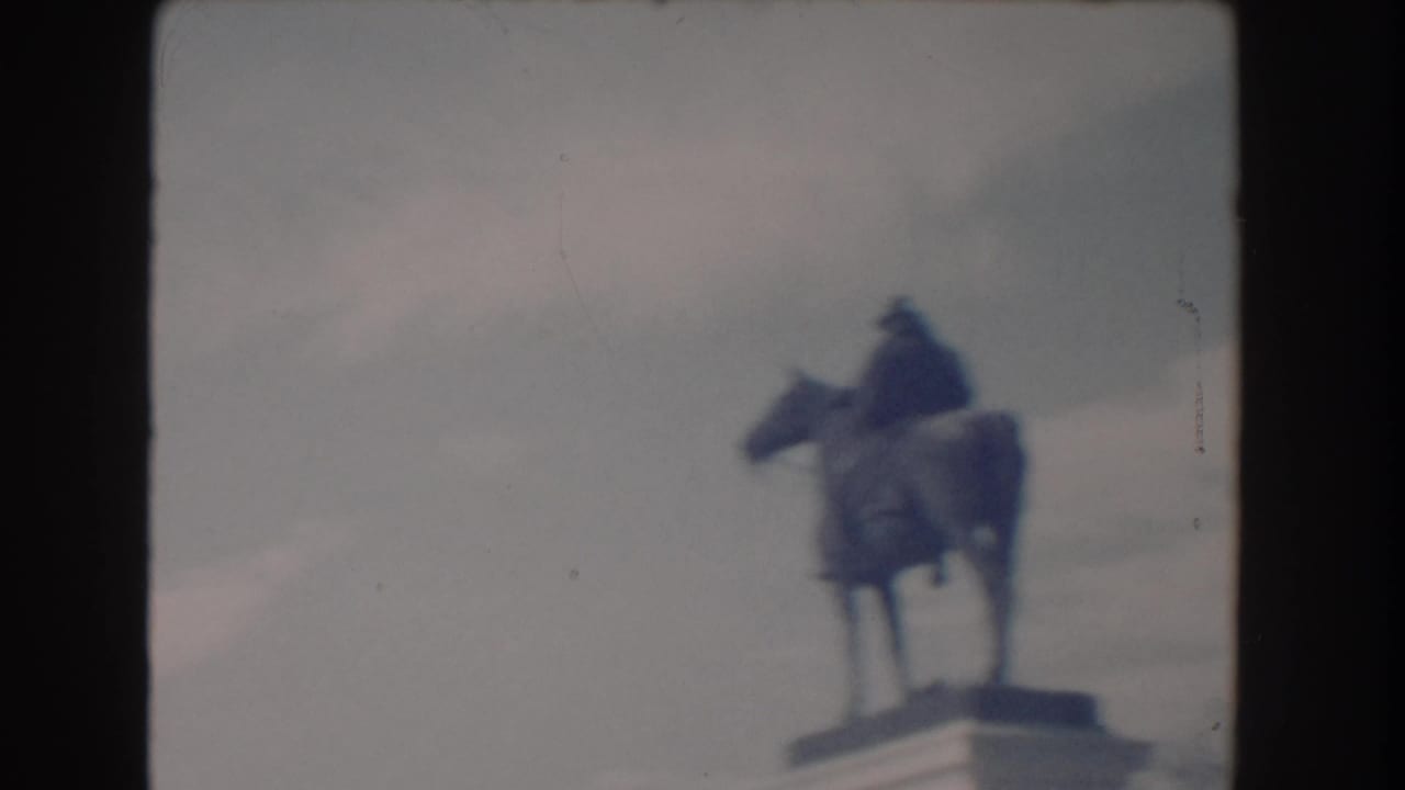 Distant equestrian statue on a pedestal, framed against an overcast sky.