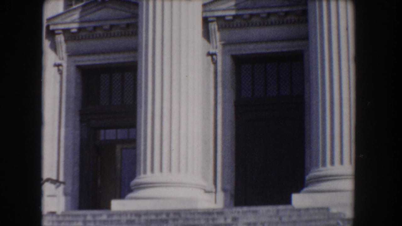 Large fluted columns and dark entry doors on a stone building facade.