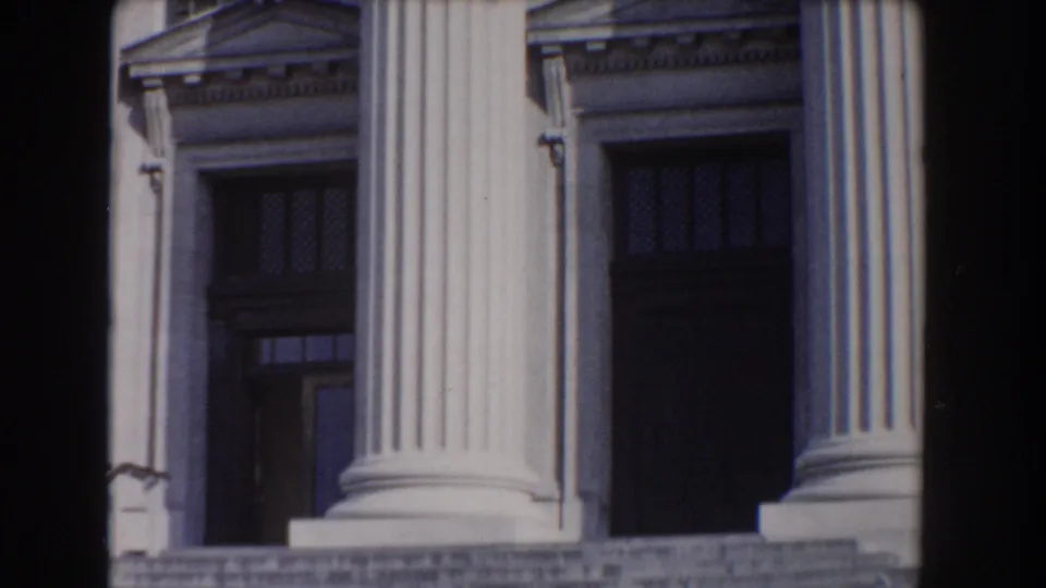 Classical stone facade in Washington, DC with tall fluted columns, pedimented details, and recessed dark doors.