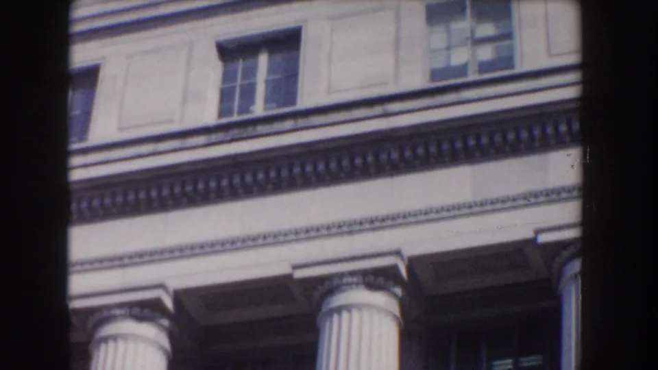 Cropped view of an ornate classical facade in Washington, DC, showing upper windows, cornice detail, and column capitals.