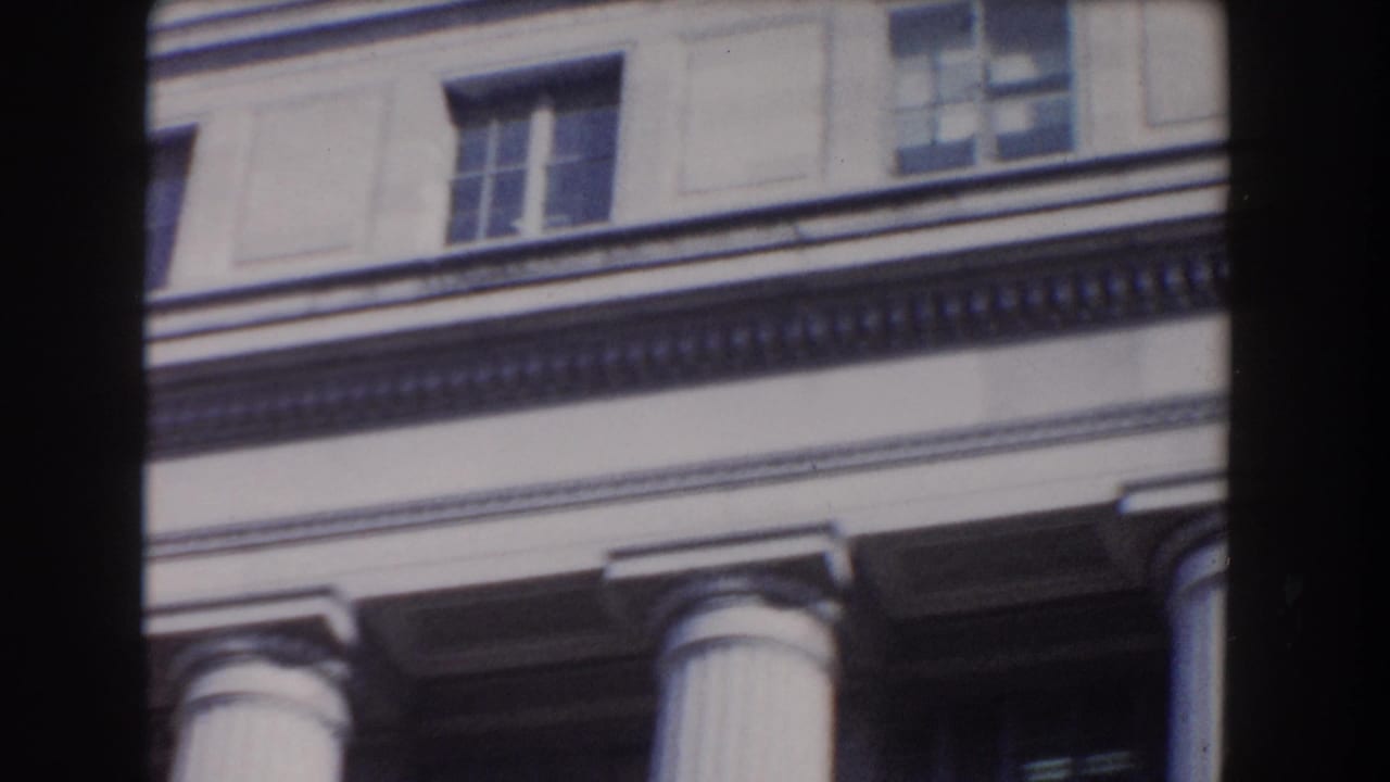 Close view of a neoclassical building facade with columns, windows, and dark film-frame edges.