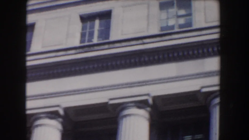 1960 Washington, DC 8mm frame showing part of a neoclassical facade with columns, upper windows, and cropped handheld framing.