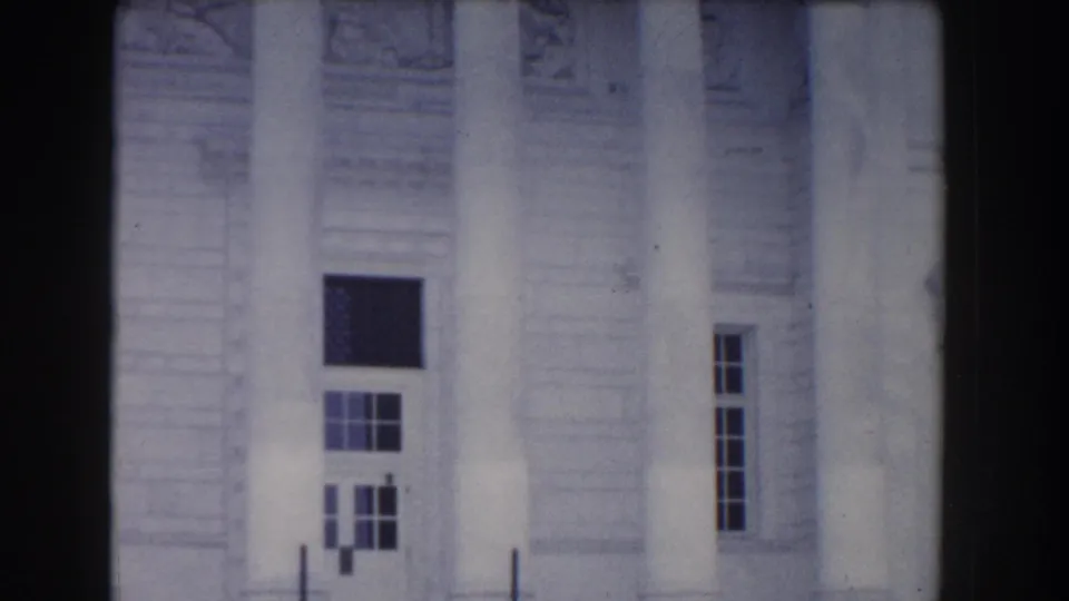 White stone building facade in Washington, DC home-movie footage, framed softly with dark film edges.