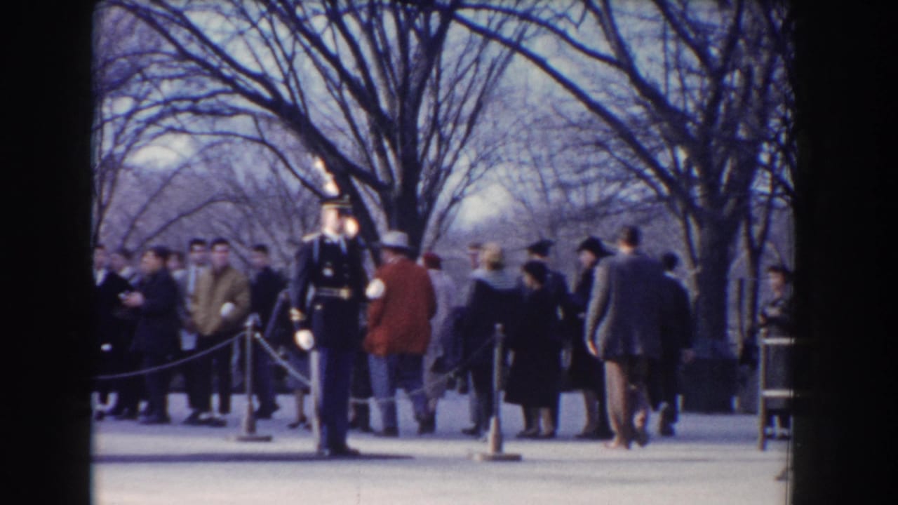 Uniformed guard with rifle stands near rope barriers as visitors gather behind him.