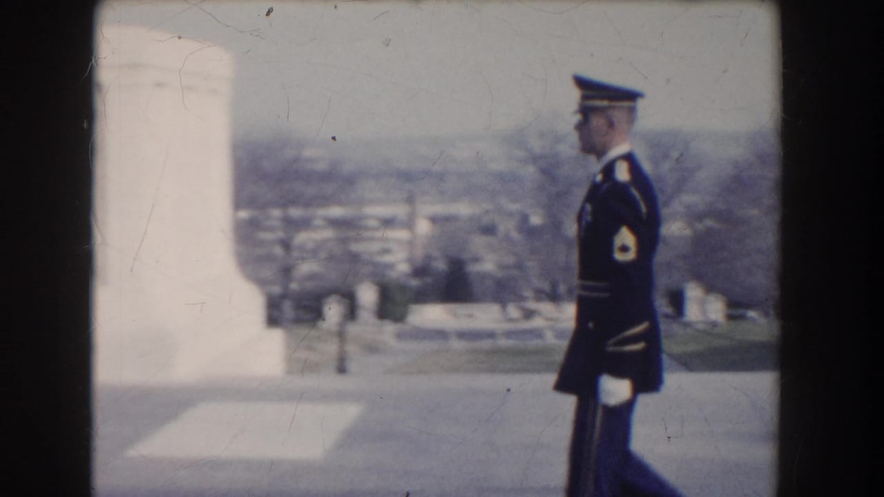Uniformed guard walking beside a white monument with distant view behind.