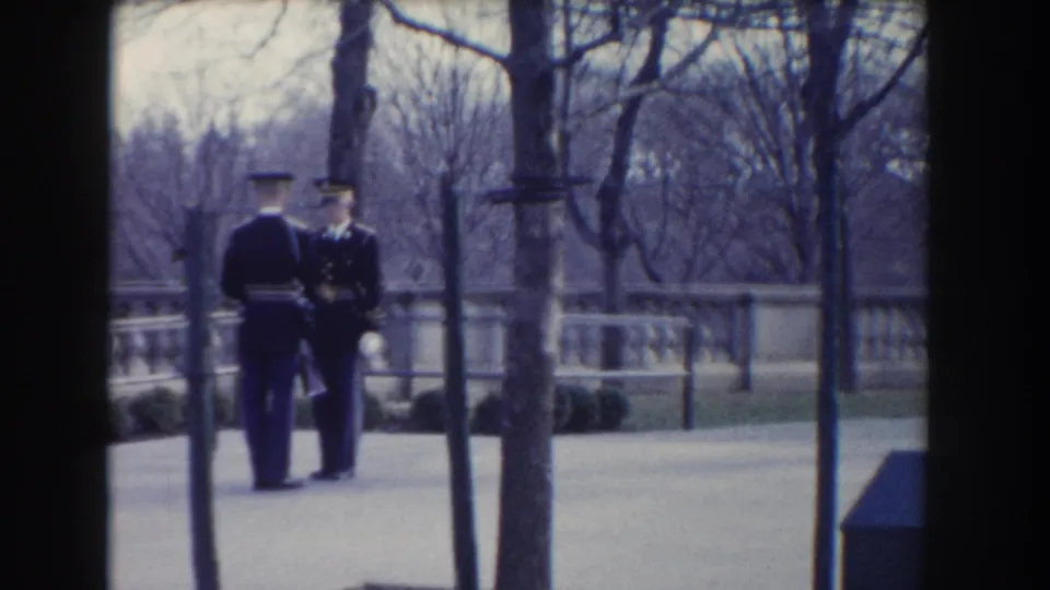 Two military guards in dark uniforms appear to pause or confer in a Washington, DC outdoor ceremonial area.
